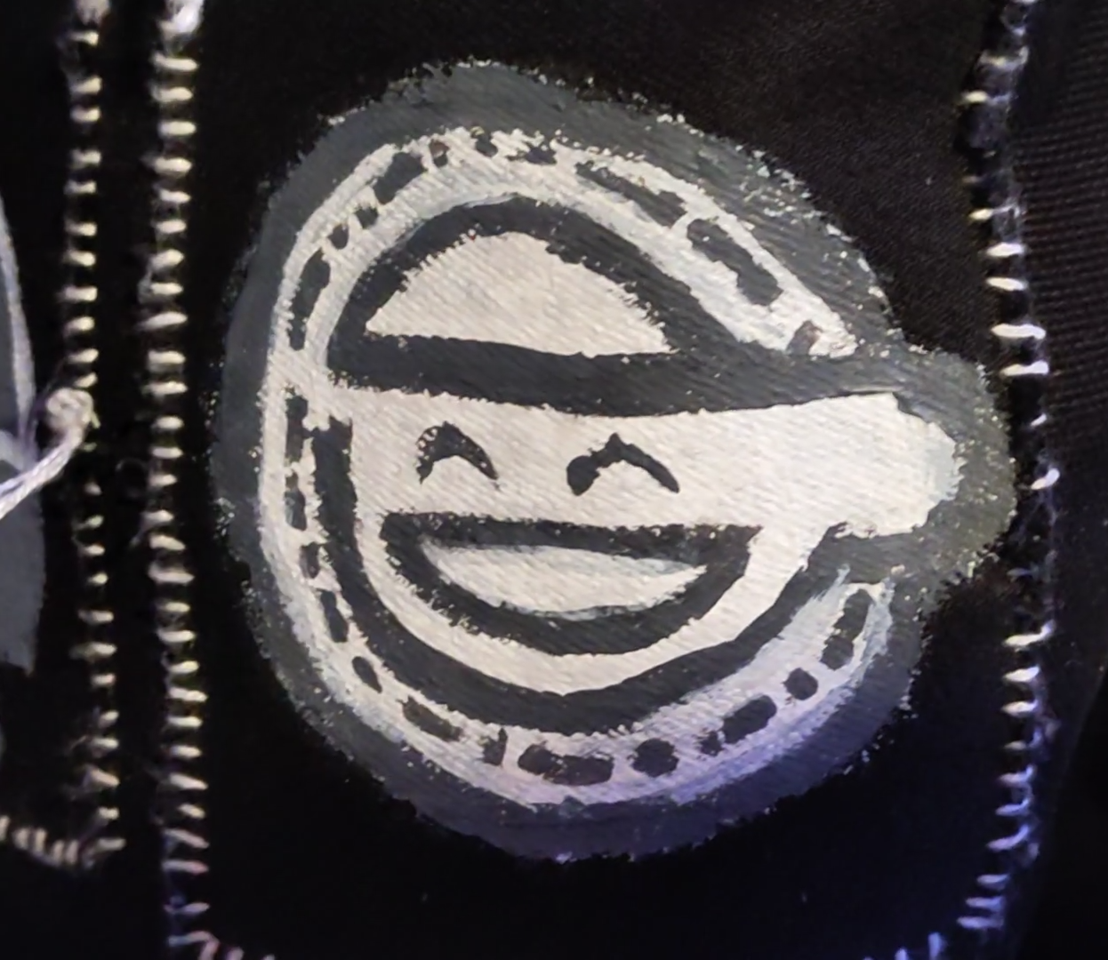 An image of a black, white and grey patch on a jacket depicting 'the laughing man''s logo from the anime series: Ghost In The Shell: Stand Alone Complex
